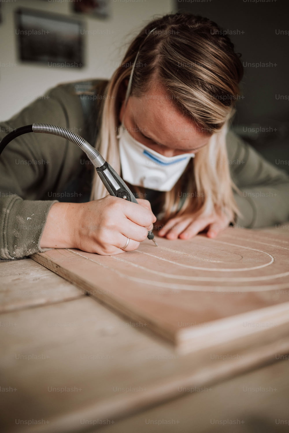 una donna che indossa una maschera facciale mentre lavora su un pezzo di legno