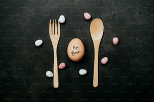a wooden spoon, fork and egg on a table
