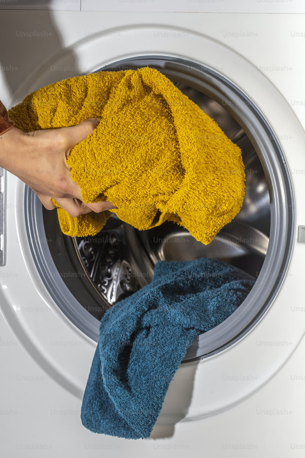 a person holding a yellow towel next to a washing machine