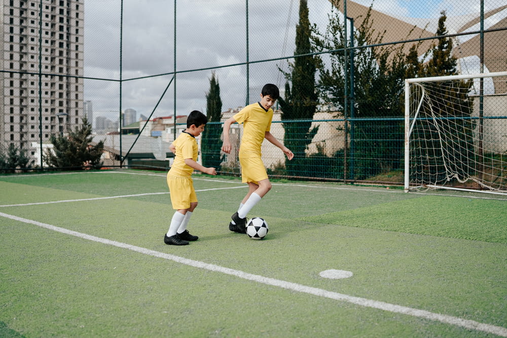 a couple of young men kicking around a soccer ball