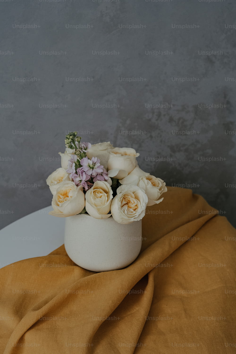 a white vase filled with white flowers on top of a table