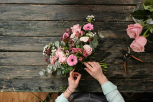 uma pessoa segurando um buquê de flores em cima de uma mesa de madeira