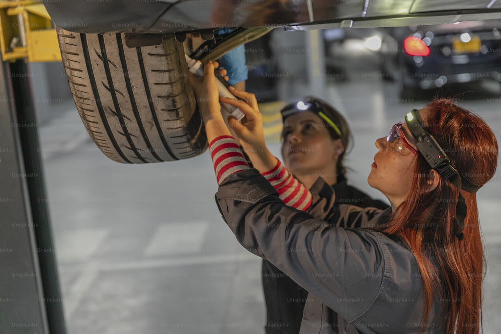 a man and a woman working on a car