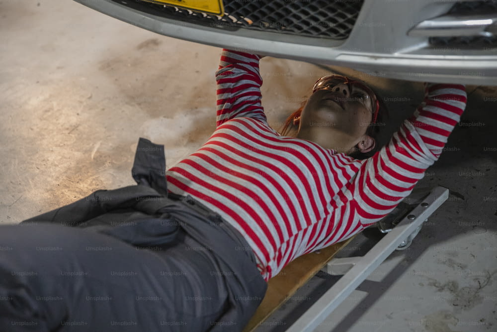 una persona sdraiata a terra sotto un'auto
