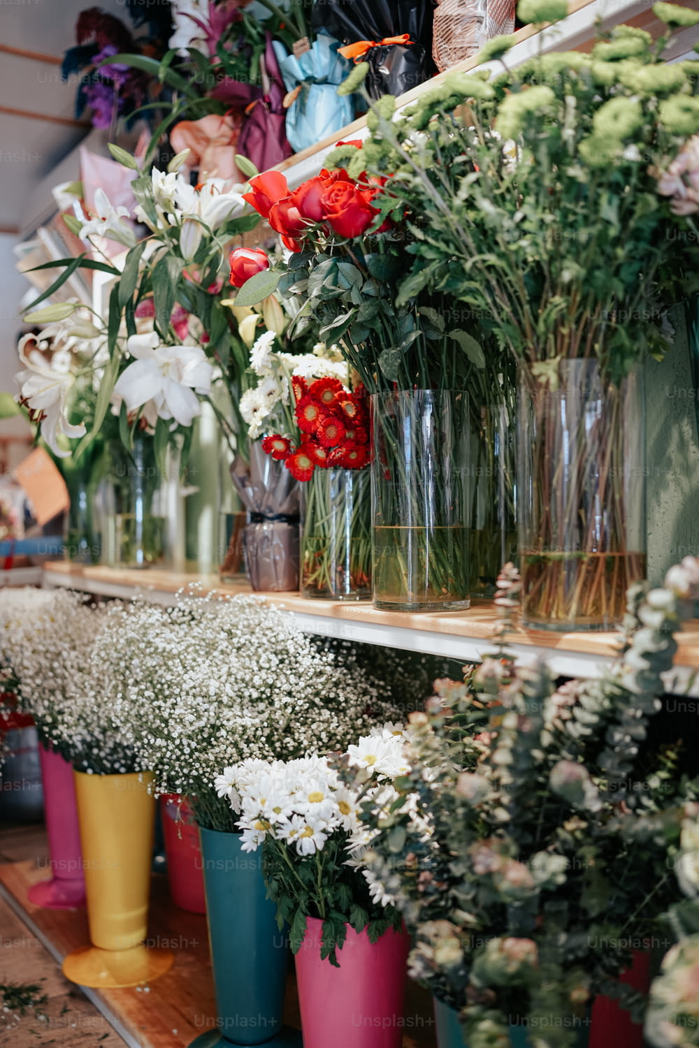 um monte de vasos cheios de flores em uma prateleira