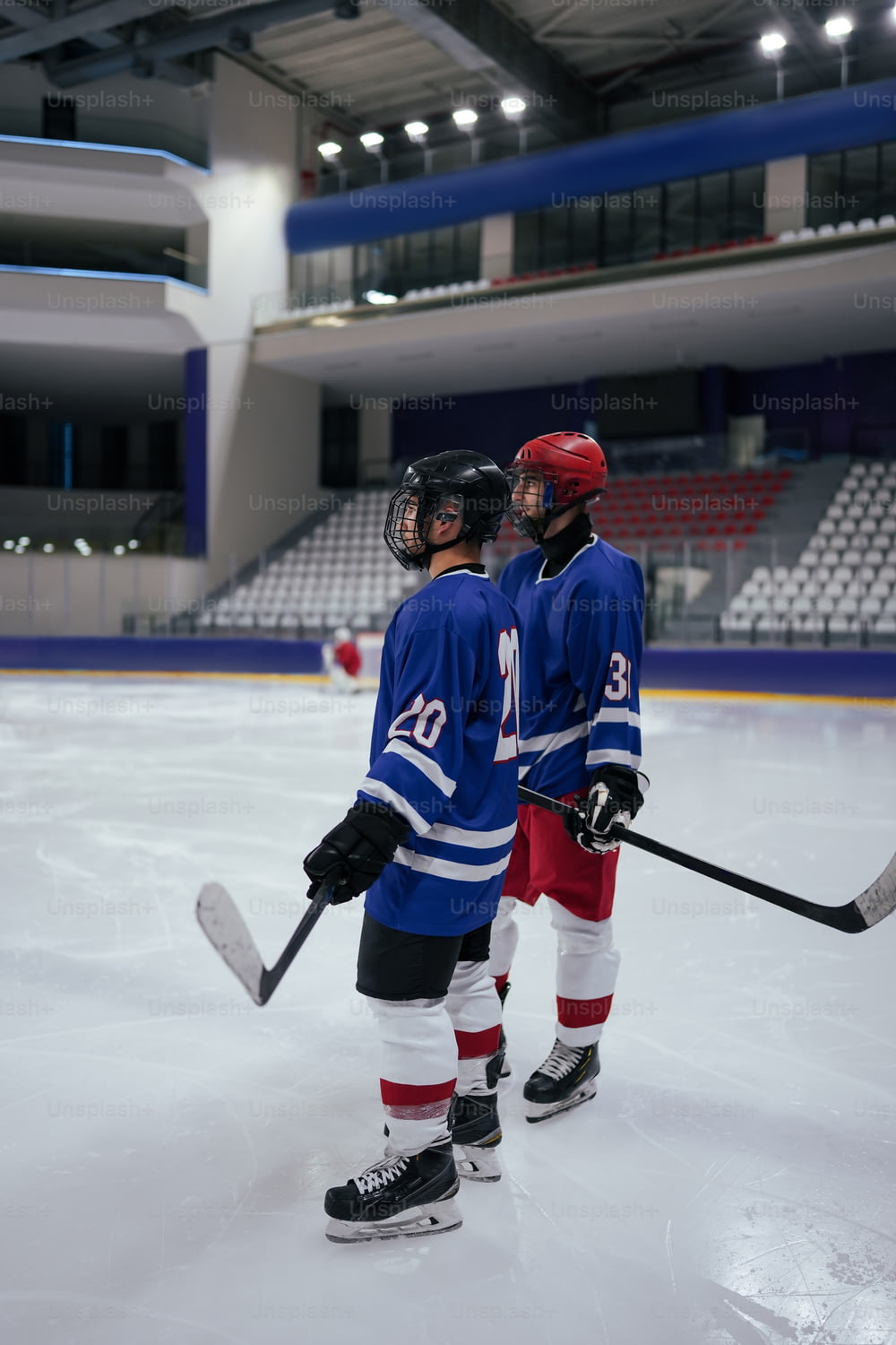 a couple of young men standing on top of a ice rink