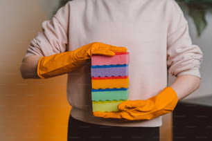 a person wearing yellow rubber gloves holding a piece of cake