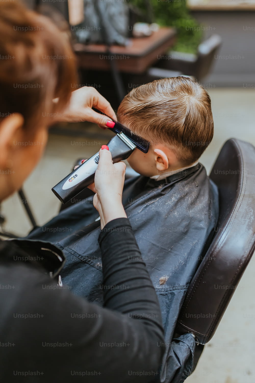 a woman is cutting a young boy's hair