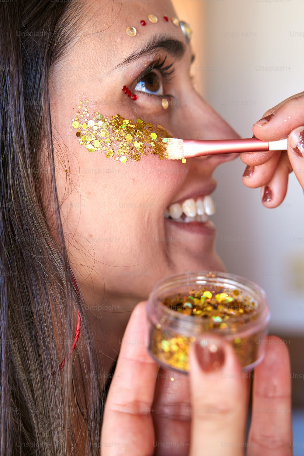 a woman is putting gold flakes on her face