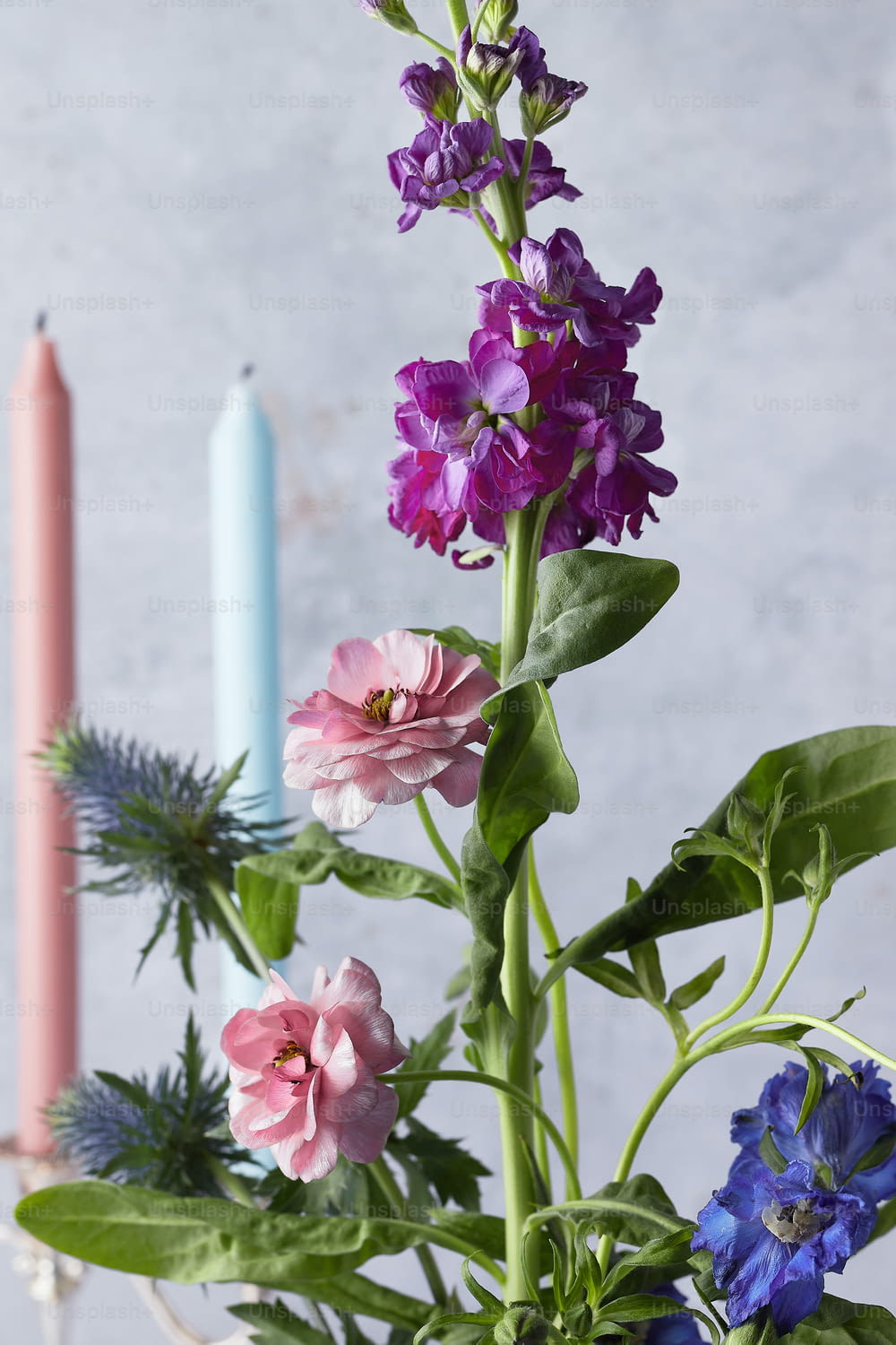 a vase filled with purple flowers next to two candles