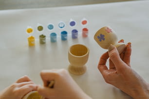 a person holding a wooden cup next to a set of small cups