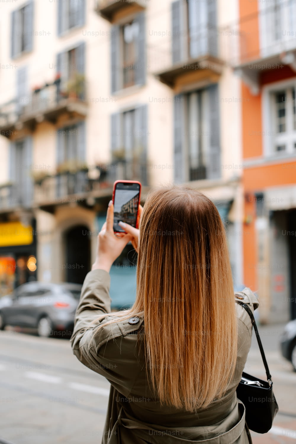 Una mujer tomando una foto de un edificio con su teléfono celular