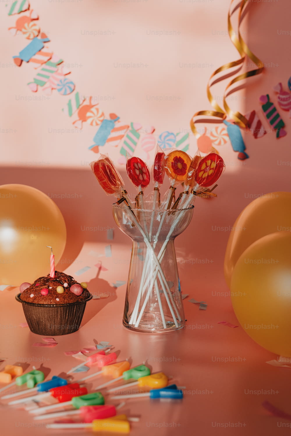 a cupcake on a table with balloons and confetti