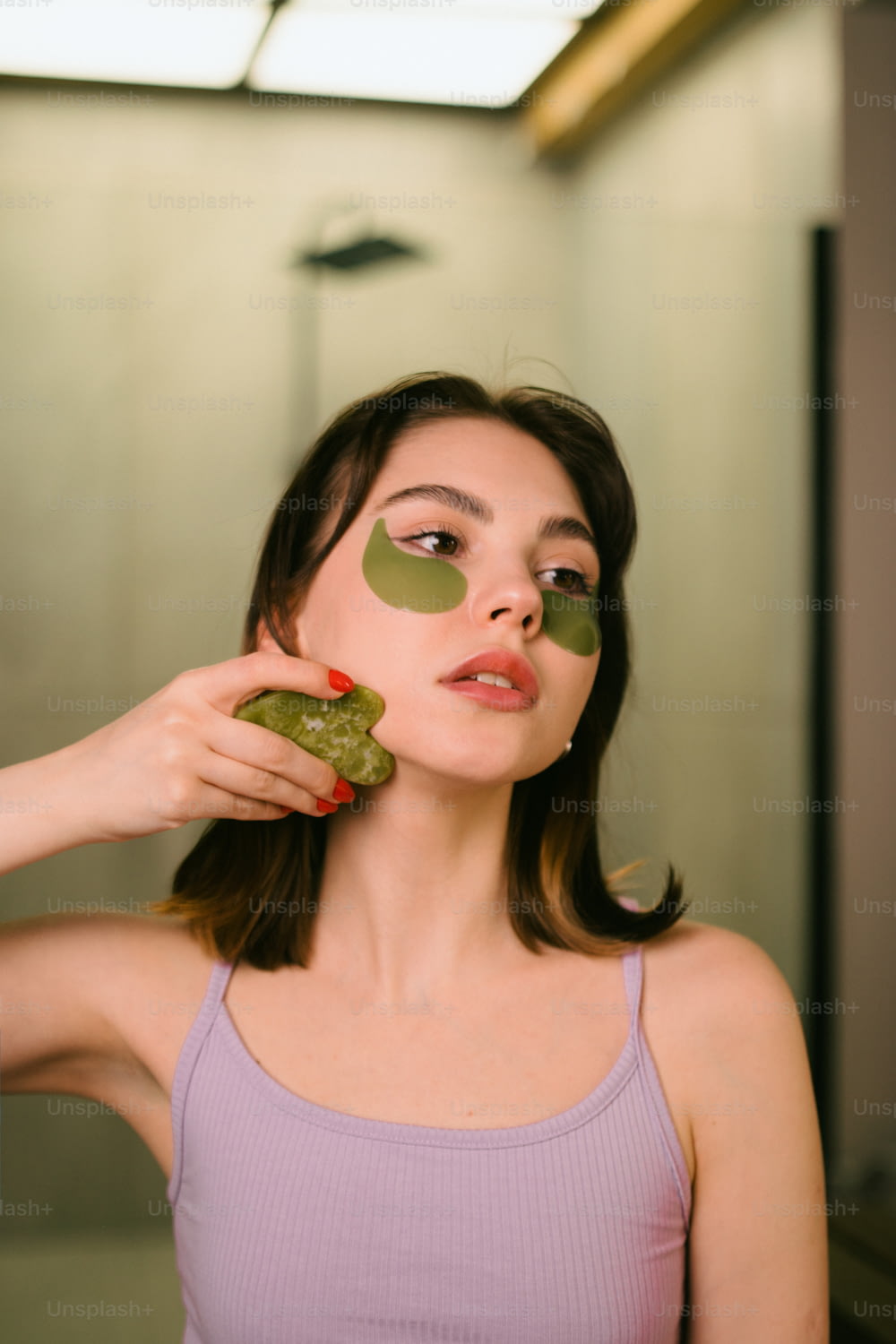 Une femme tenant un morceau de concombre devant son visage