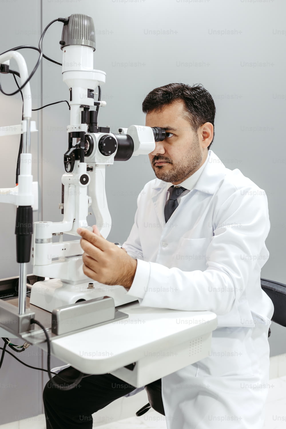 a man in a white lab coat looking through a microscope