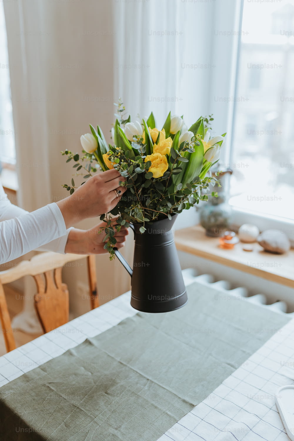 uma pessoa segurando um vaso com flores em uma mesa