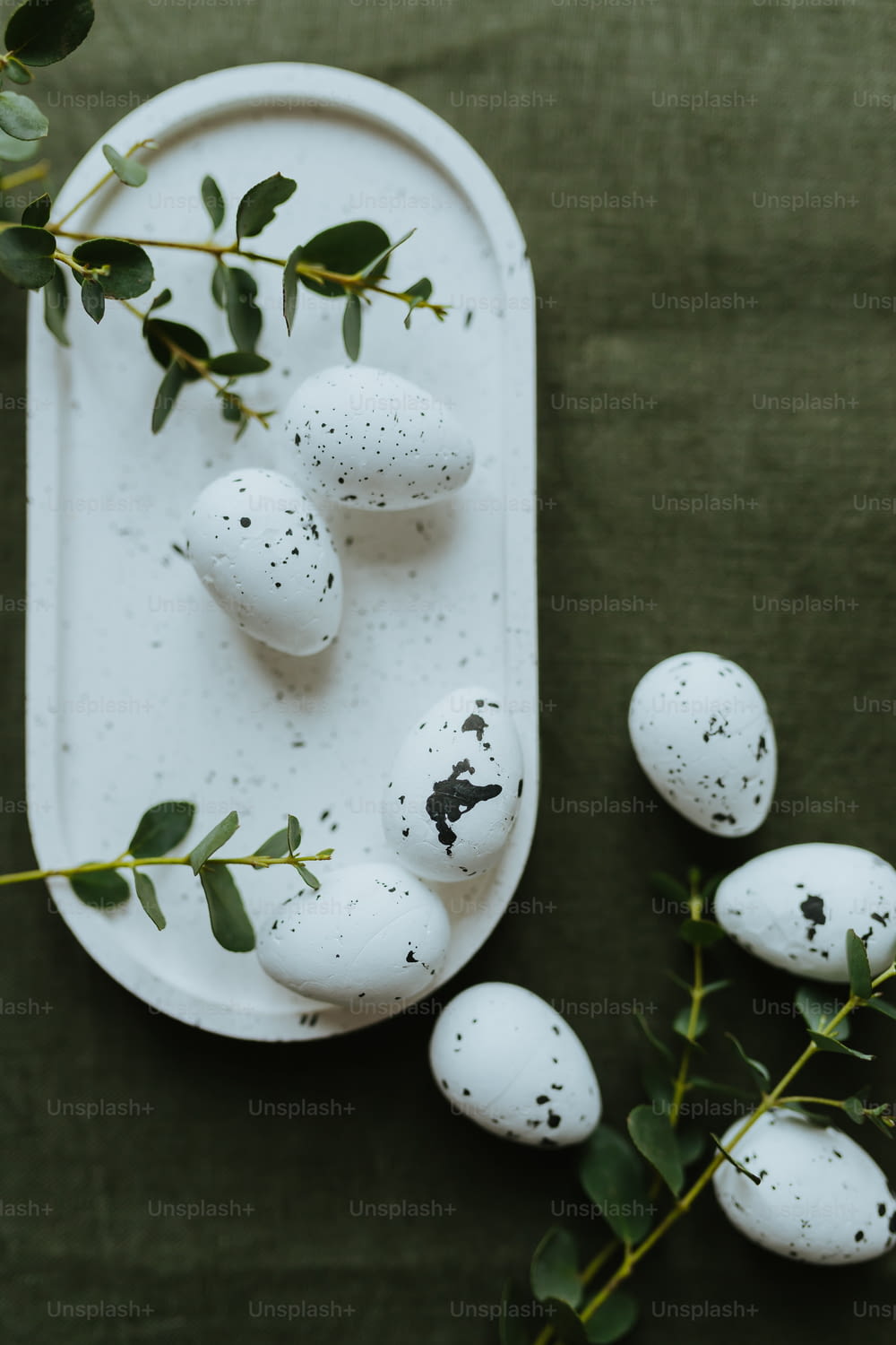 uma bandeja branca coberta com ovos brancos ao lado de folhas verdes
