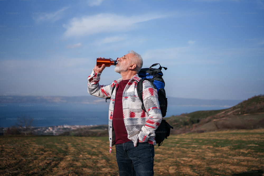 Ein Mann mit einem Rucksack trinkt aus einer Flasche