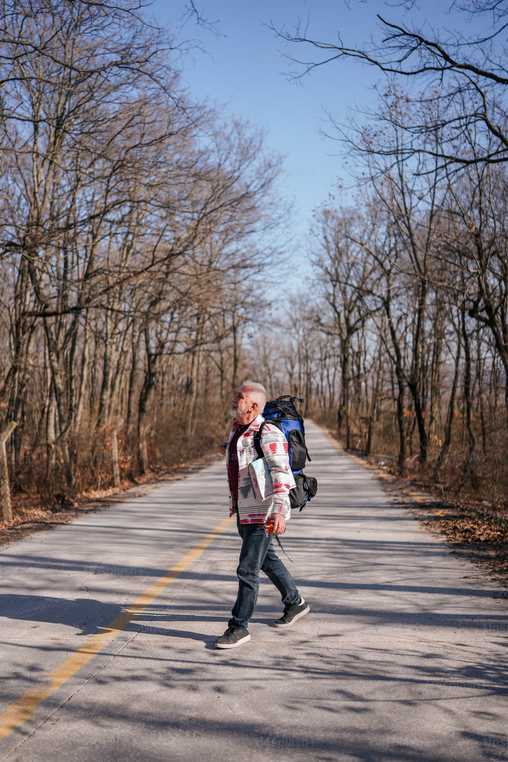 Ein Mann geht mit einem Rucksack auf dem Rücken eine Straße entlang
