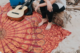 a woman sitting on a blanket next to a guitar