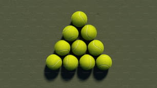 a pyramid of tennis balls on a green surface