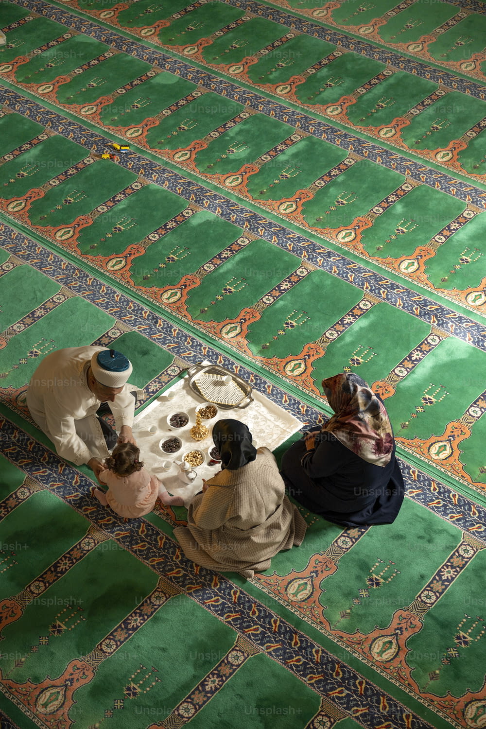 a group of people sitting on top of a green rug