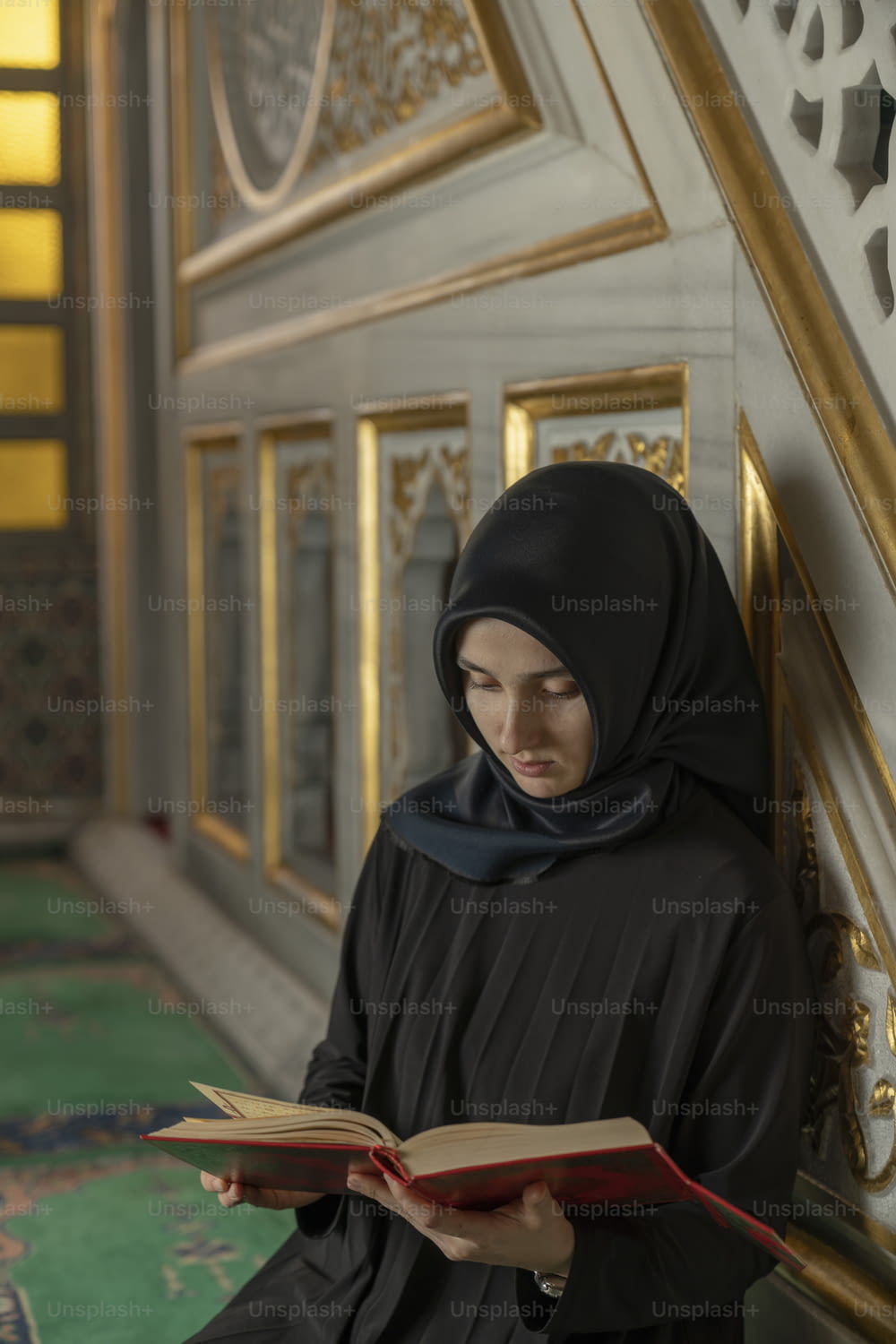 a woman in a black hijab is reading a book