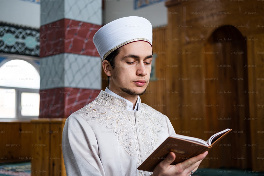 a man in a white outfit is reading a book