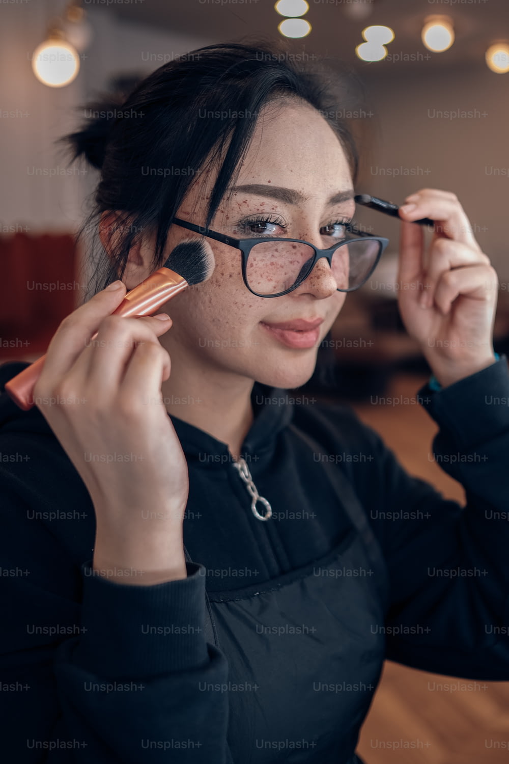 uma mulher com óculos segurando uma escova em seu olho