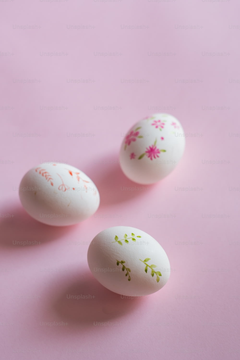 tre uova decorate sedute sopra una superficie rosa
