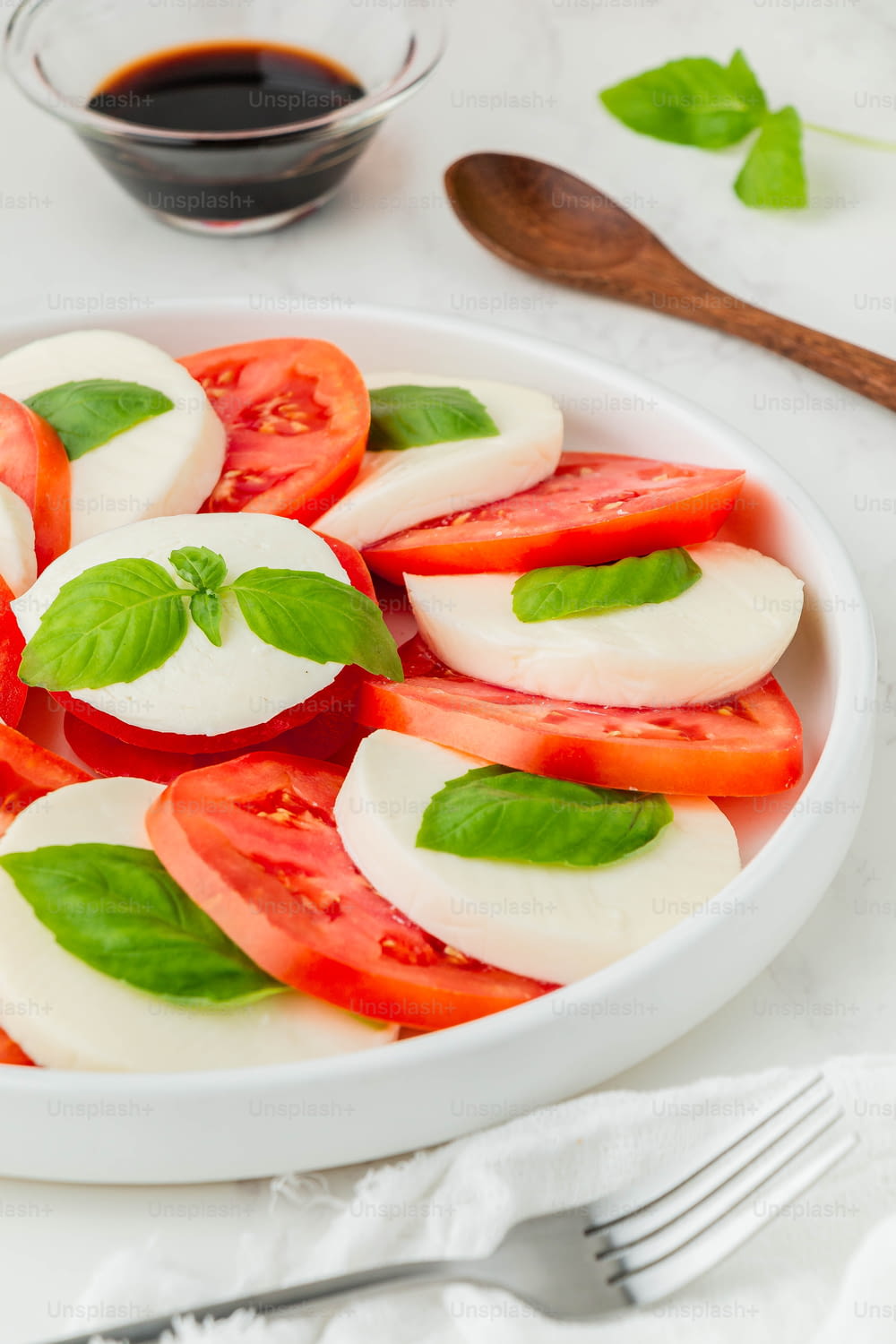 a white plate topped with sliced tomatoes and mozzarella