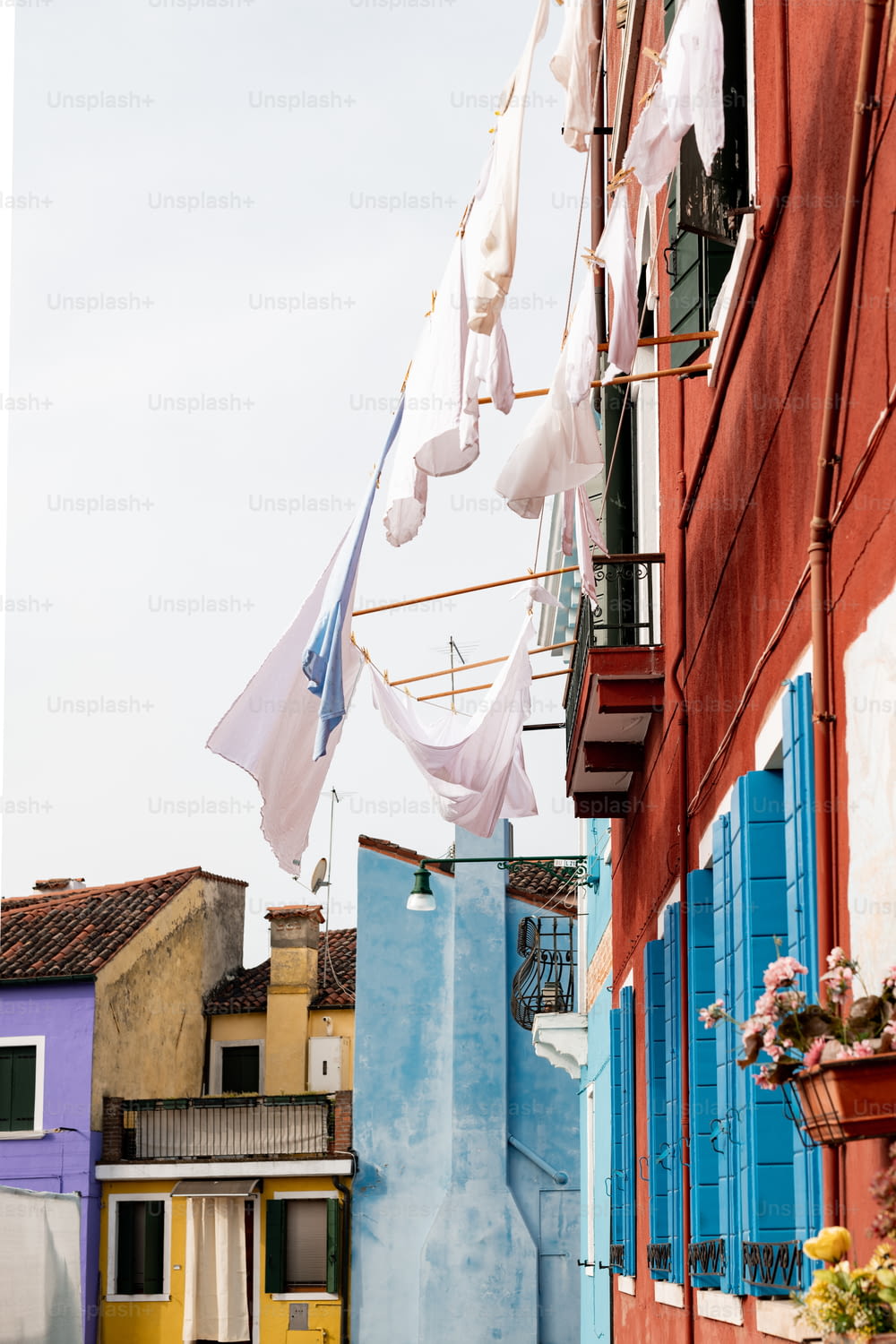 a row of blue and yellow buildings with laundry hanging from them