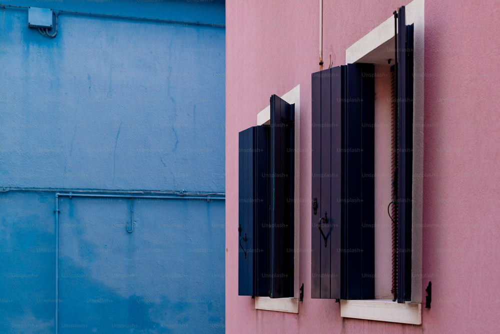 ein rosa-blaues Gebäude mit zwei Fenstern