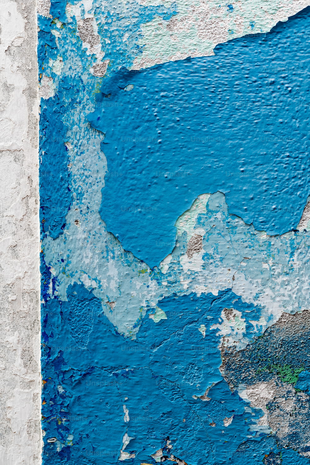 a blue and white wall with peeling paint