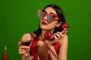 Una mujer con un vestido rojo sosteniendo una copa de vino y un teléfono