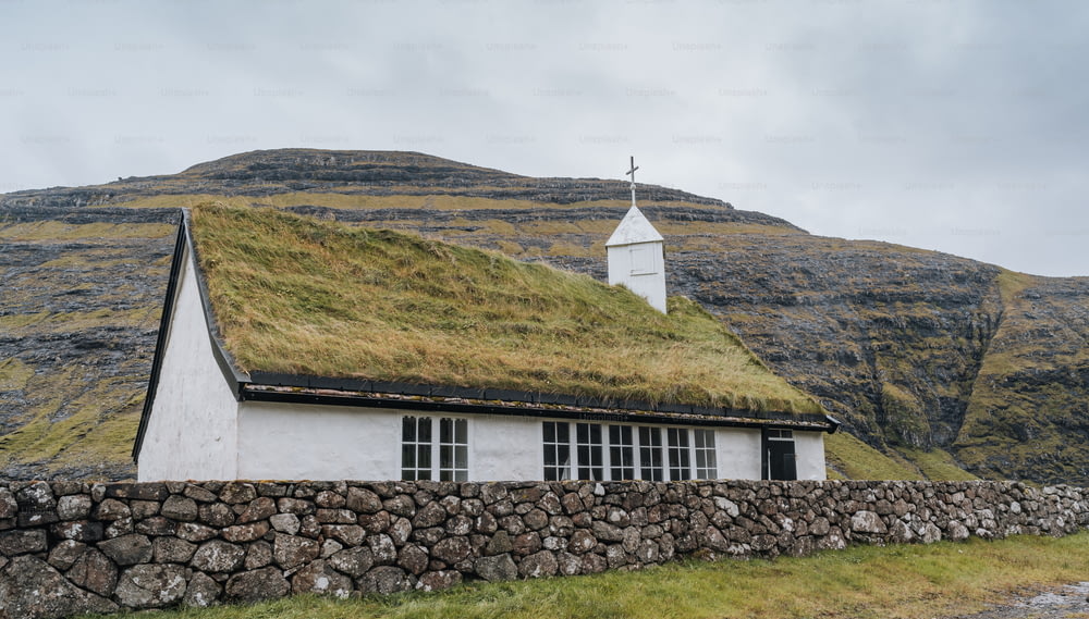 una casa con un tetto d'erba e un muro di pietra