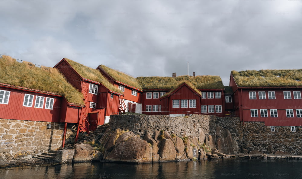 eine Reihe roter Häuser mit Grasdächern neben einem Gewässer