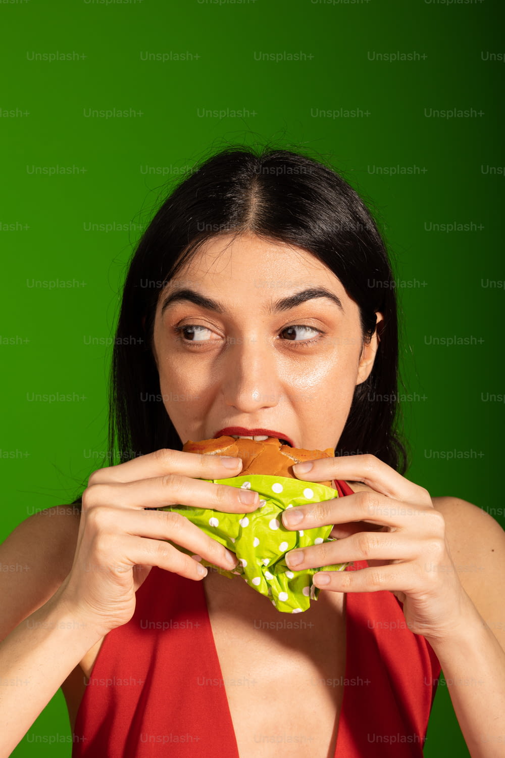 Une femme en robe rouge mangeant un sandwich
