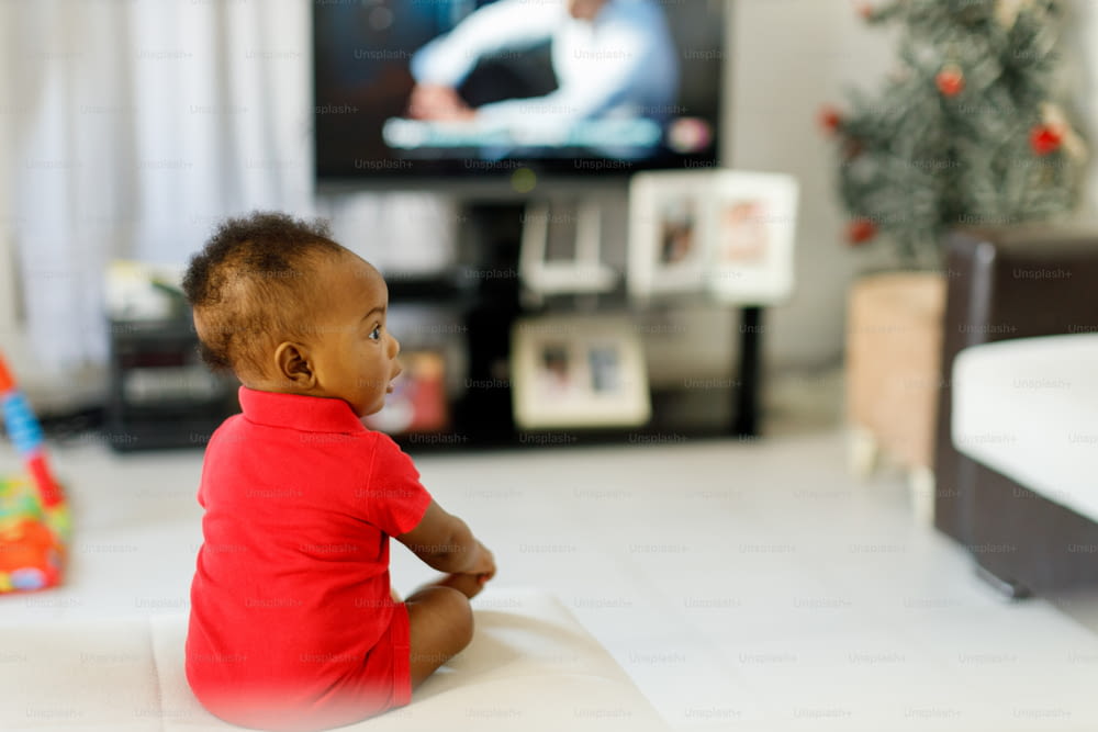 a baby sitting on the floor in front of a tv