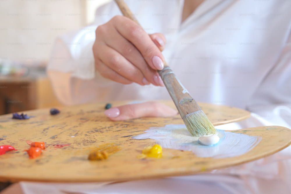 a person holding a paintbrush on a wooden tray