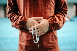 Un hombre sosteniendo un rosario en sus manos