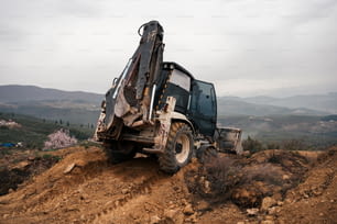 a dump truck on a dirt hill with mountains in the background