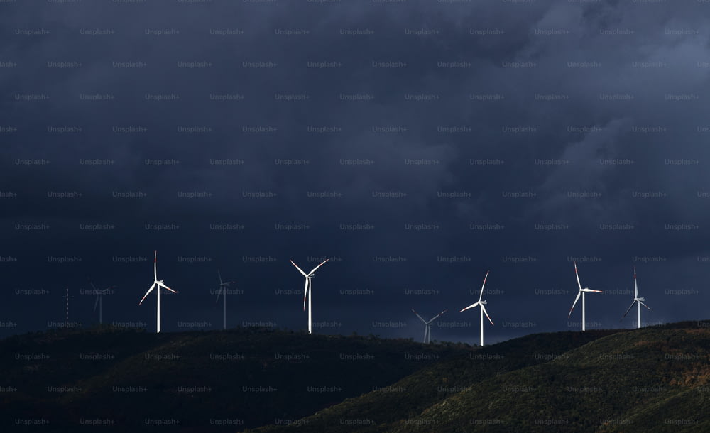 a group of windmills on a hill under a dark sky