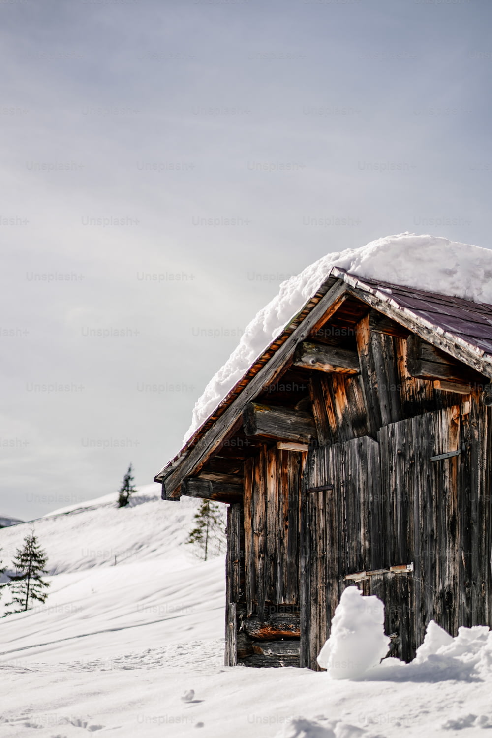 a small wooden building with snow on top of it