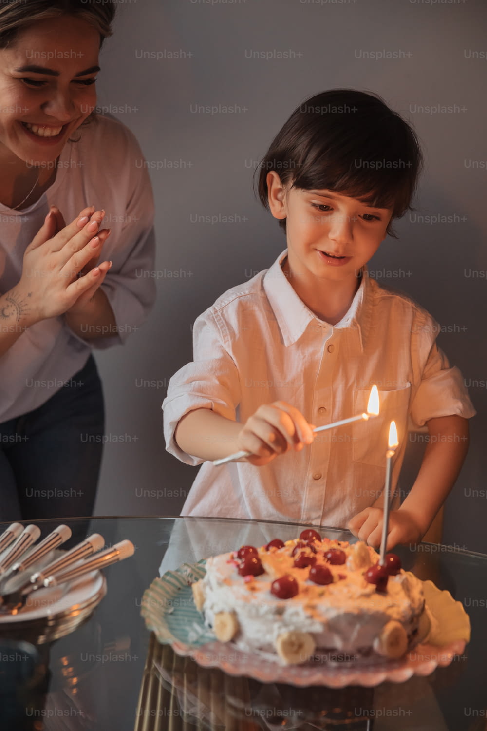 a woman and a young boy blowing out candles on a cake