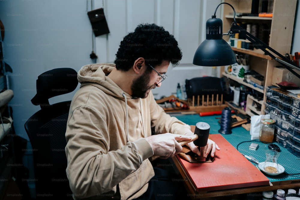 Un uomo seduto a una scrivania che lavora su un pezzo di legno