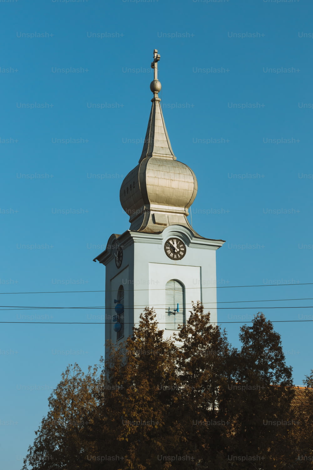 ein hoher weißer Glockenturm mit einer Uhr an jeder Seite