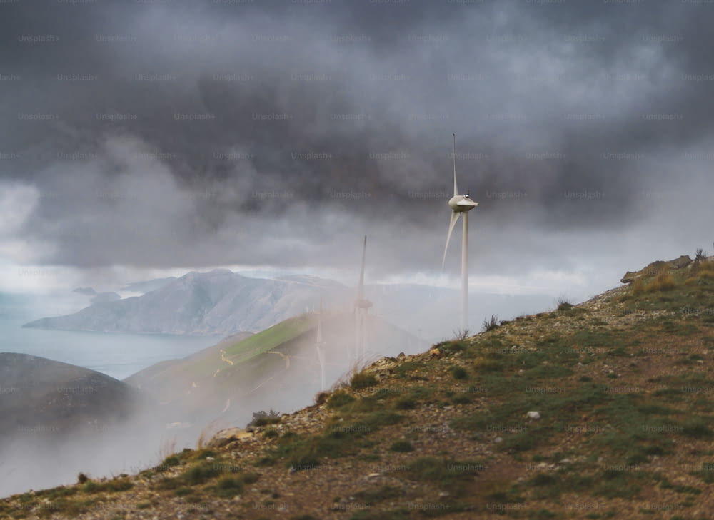 una turbina eólica en una colina con un cuerpo de agua en el fondo