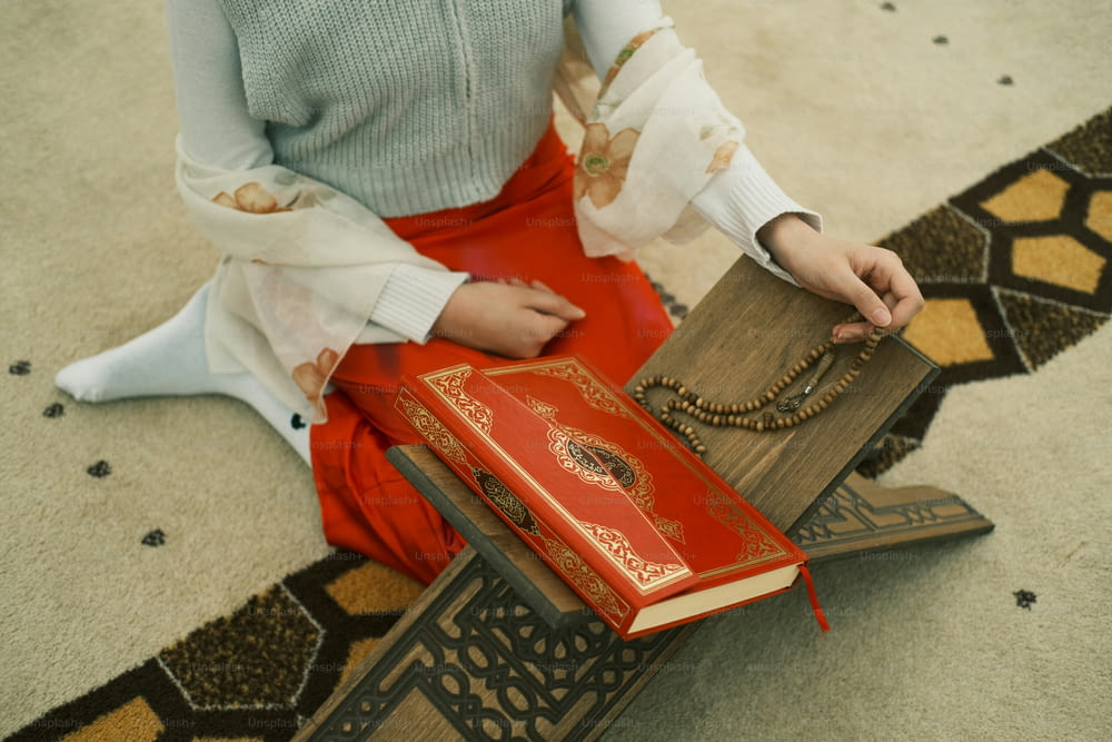 una donna seduta sul pavimento con in mano un libro