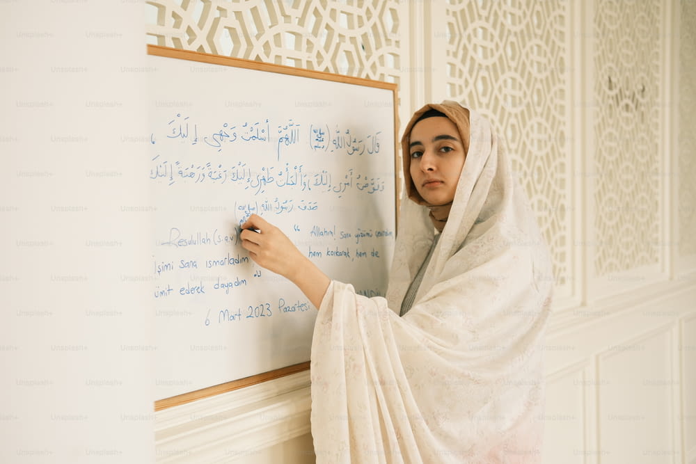 Une femme écrivant sur un tableau blanc dans une pièce